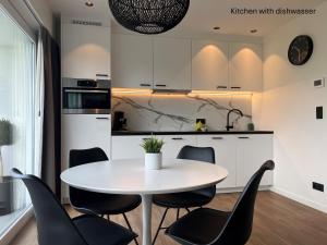 a kitchen with a white table and black chairs at Appartement ‘W Vacantia’ in De Haan