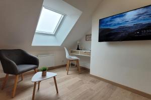 a living room with a chair and a tv on a wall at Le Perchoir - EasyEscale in Nogent-sur-Seine