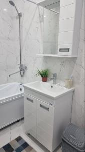 un bagno bianco con lavandino e specchio di Квартира на этаже мечты ad Aqtau