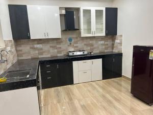 a kitchen with black and white cabinets and a refrigerator at Urban Zen Oasis - Independent floor in City Centre in Gwalior
