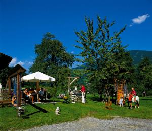 un grupo de personas sentadas en la hierba con un parque infantil en Palfnerhof Appartements, en Sankt Johann im Pongau