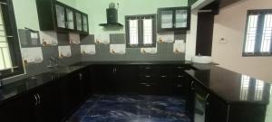 a large kitchen with black cabinets and windows at Skanda Gardens in Tittai