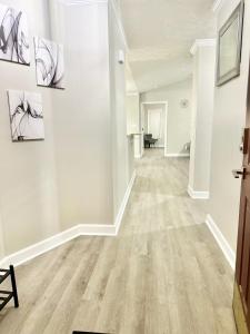 an empty living room with white walls and wood floors at Haven Away From Home Ideal For Long Term Stays in Fayetteville