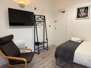 a bedroom with a bed and a chair and a television at Cosy Studio Central Colwyn Bay F2 in Colwyn Bay