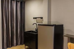 a kitchen with a sink and a black refrigerator at โรงแรมเกิดมานอน ขอนแก่น in Khon Kaen