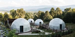 WojcieszyceIdea by Glamp的山丘上四座圆顶建筑，背景是连绵的群山。