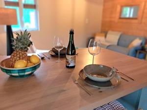 a table with a bottle of wine and a bowl of fruit at Chalet de Lanvaux in Saint-Jean-Brévelay