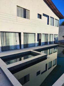 a house with a swimming pool in front of a building at 11Suites casa Suite #7 in Caraguatatuba