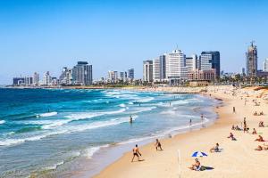 eine Gruppe von Menschen am Strand vor einer Stadt in der Unterkunft Sea Land Suites in Tel Aviv