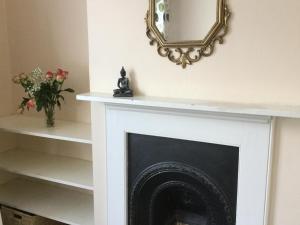 a mirror above a fireplace with a vase of flowers at Victorian Period Central Home in Cambridge