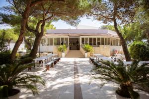 a building with tables and benches and trees at Camping Village Baia Falcone in Vieste