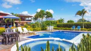 a pool with chairs and tables and umbrellas at Finca Hotel los Alpes in Quimbaya +33 photos