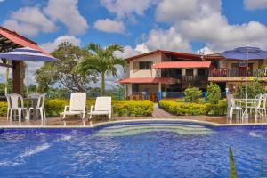a pool with chairs and umbrellas in front of a house at Finca Hotel los Alpes in Quimbaya
