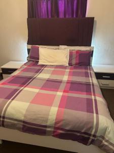 un letto con una coperta scozzese colorata e cuscini di Skyline Self Service a Leigh