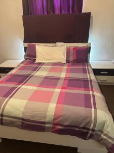 un letto con una coperta scozzese colorata e cuscini di Skyline Self Service a Leigh