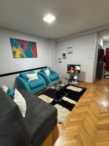 a living room with two blue couches and a tv at M&G centar grada in Požarevac