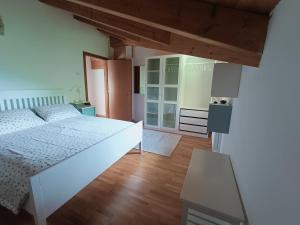 a bedroom with a white bed and a wooden floor at Casa del ruscello in Mezzana