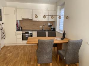 a kitchen with white cabinets and a wooden table and chairs at Albarosa Appartemant in Öblarn