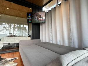 a living room with a couch and a flat screen tv at Cabana Black BIRD l, morro da igreja Urubici SC in Urubici