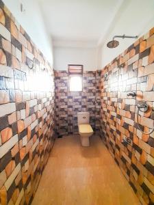 a bathroom with a toilet and a tile wall at Rasana Breezt Villa in Matara