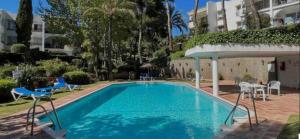 einen Pool mit Stühlen, einem Tisch und einem Gebäude in der Unterkunft Estudio Glamuroso cerca de la playa en Mijas Costa in Málaga