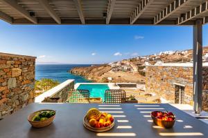 a table with bowls of fruit on a balcony with the ocean at Phos Villas Tinos in Agios Romanos