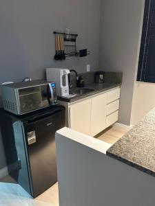 a small kitchen with a microwave and a refrigerator at Kit 102 Brasília in Brasilia