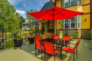 - une table et des chaises avec un parasol rouge sur la terrasse dans l'établissement Gîte Les Pignons, à Saint-Damien