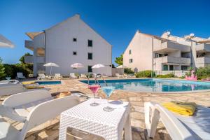 a patio with a table with a drink on it next to a pool at Apartment Milna - with Swimming Pool & Amazing Seaviews, above Bijaka Beach in Milna