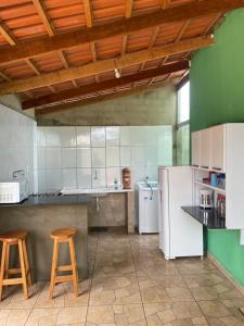 a kitchen with two stools and a white refrigerator at Casa fechada in Pirenópolis