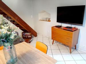 ein Wohnzimmer mit einem Tisch und einem TV auf einer Kommode in der Unterkunft Evasion vintage in La Sauvetat