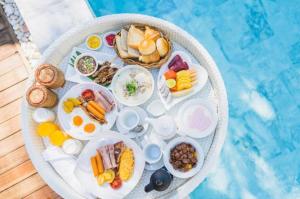 a tray of breakfast foods on a table next to a pool at Kondey Villas in Kondey