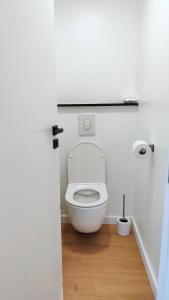 a white toilet in a bathroom with a wooden floor at Le Cocon Studio in Brussels