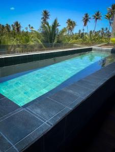 a swimming pool with turquoise water and palm trees at Milagres Hospedagens - Praia e Vista Coqueiros in São Miguel dos Milagres