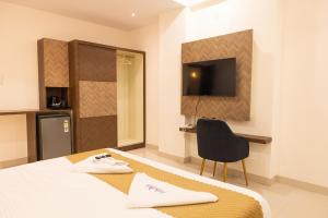 a room with a bed and a chair and a television at Hotel Radhe Pride Hitech City in Hyderabad