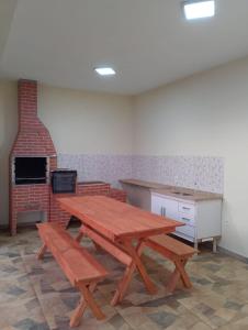 a picnic table and benches in a room with a brick oven at Green Home in Águas de Santa Barbara