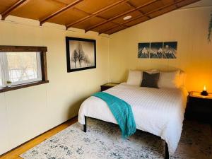 a bedroom with a bed with a blue blanket on it at Abandoned Rail Cabin -19 miles to Breckenridge! Hot Tub! in Fairplay