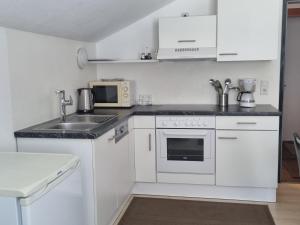 eine weiße Küche mit Spüle und Mikrowelle in der Unterkunft Haus Aras in Prutz