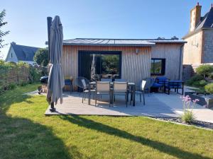 Un patio con una mesa y sillas y una sombrilla. en Île Grande, Location maison saisonnière chez Dom et Cathy C, en Pleumeur-Bodou