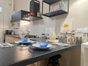 a kitchen with two plates and wine glasses on a counter at No Name Prestige Apartment in Bologna