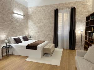 a bedroom with a white bed and a brick wall at No Name Prestige Apartment in Bologna