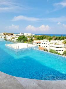 a large blue swimming pool with buildings in the background at Tu estancia perfecta - ubicación y privacidad in Playa del Carmen