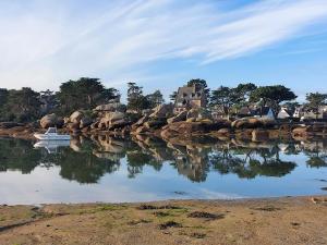 un barco está sentado en el agua cerca de algunas rocas en Île Grande, Location maison saisonnière chez Dom et Cathy C, en Pleumeur-Bodou 23 fotos más