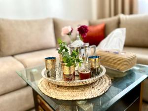 a glass table with a tray of drinks on it at S&H Home Martil Apartment in Martil