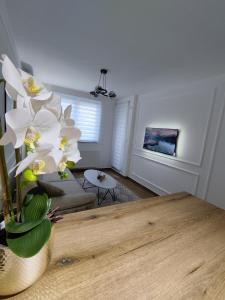 a living room with a table and white flowers at Mozart apartman in Bijeljina