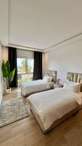 ein Schlafzimmer mit zwei Betten und einem großen Fenster in der Unterkunft N9 Appartement pied sur mer, La Corniche Rabat in Rabat