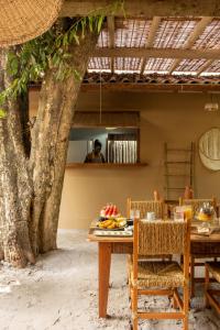 a table and chairs next to a tree at Villa Rio Caraiva in Caraíva