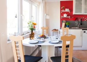 uma pequena cozinha com uma mesa branca e cadeiras em Toplage direkt an der Steilküste - FeWo 2 "Ostseenest" Hohwacht em Hohwacht mais 23 fotografias