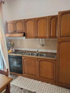 a kitchen with wooden cabinets and a sink at Appartamento Ficarra Via Logge 16 in Ficarra