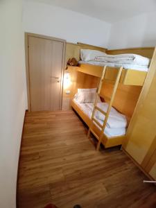 a small room with two bunk beds and a wooden floor at la fonte in Sporminore +15 photos